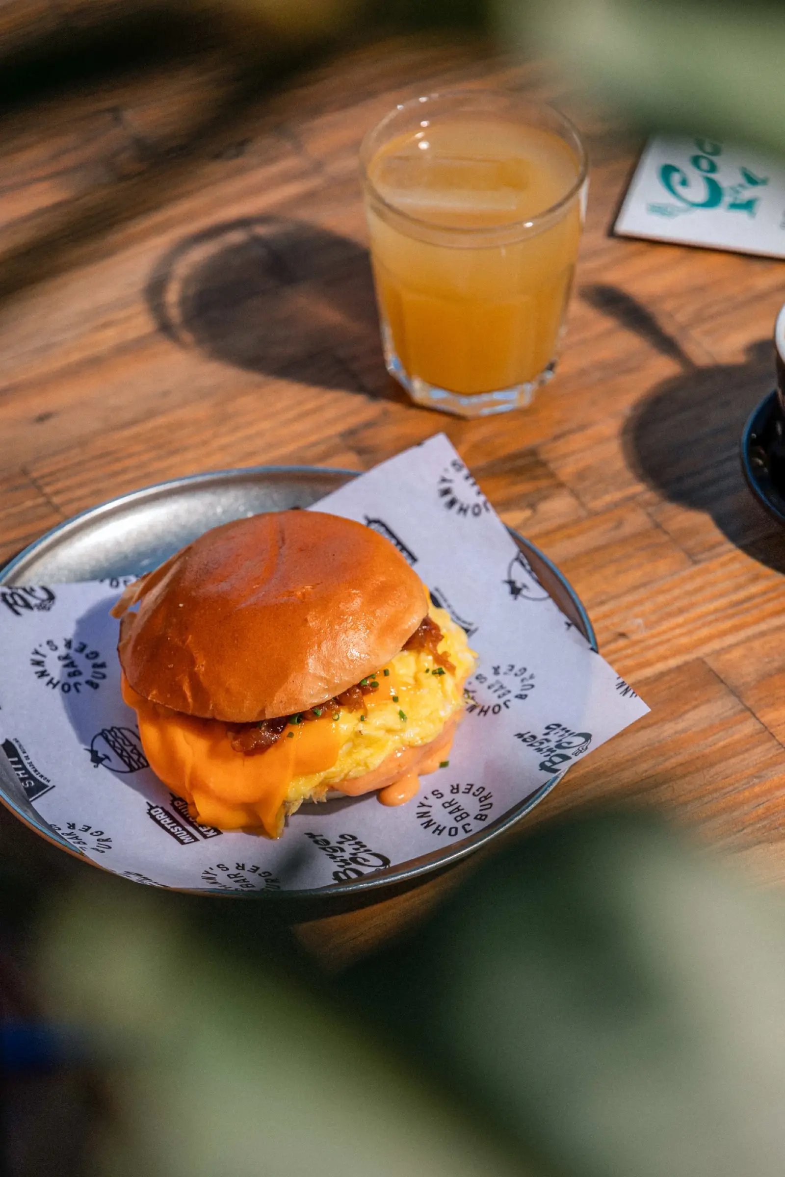 Bocadillo de huevo revuelto con cheddar y bacon del brunch, con zumo de naranja