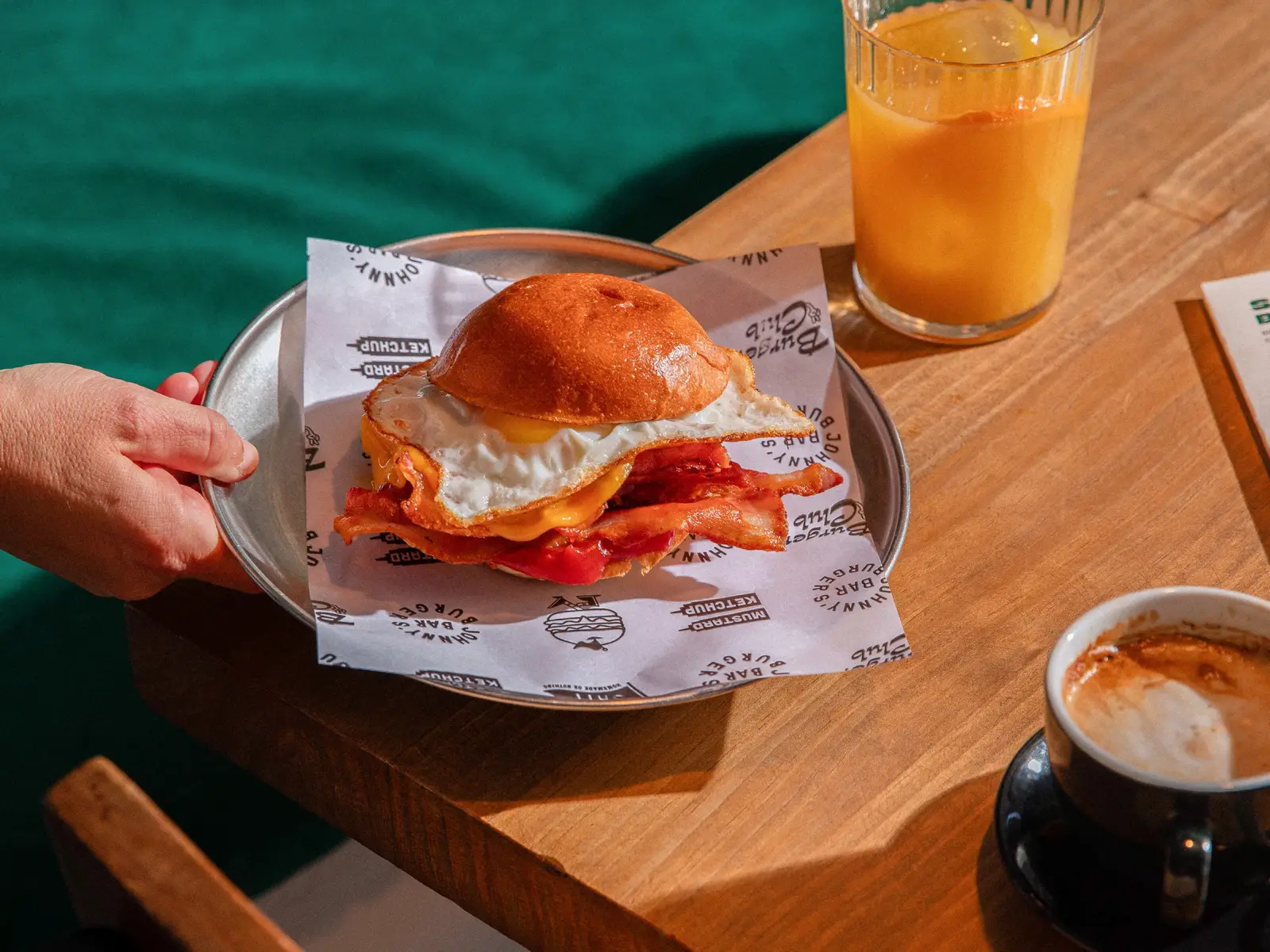 Bocadillo de huevo frito, bacon y cheddar servido con zumo y café
