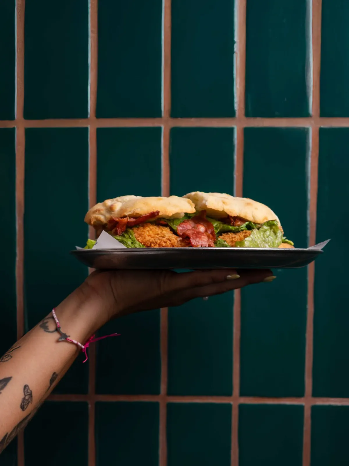 Sándwich de pollo crujiente con bacon servido en mano
