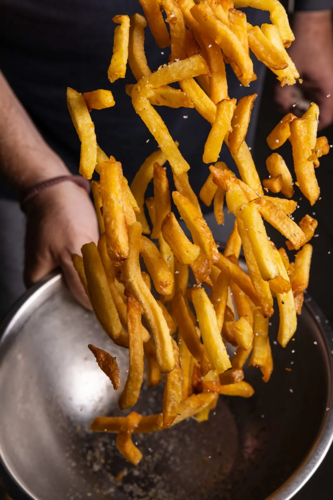 Patatas fritas caseras saltando en sartén con sal