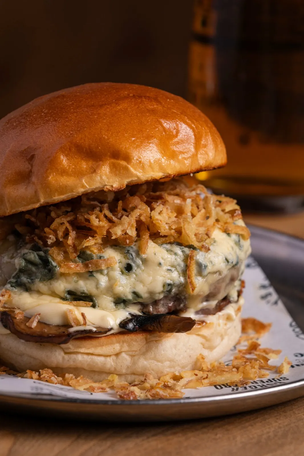 Burger con queso fundido, cebolla crujiente y setas