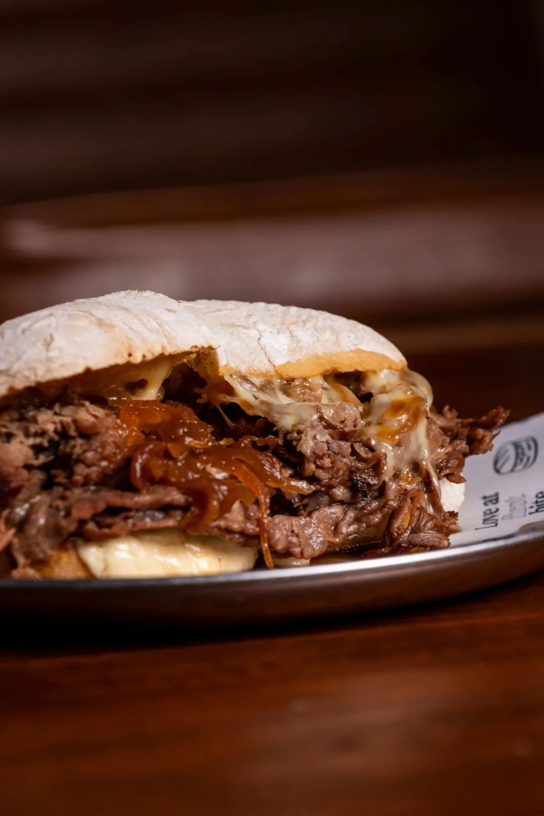Sándwich de carne deshilachada con cebolla caramelizada y queso